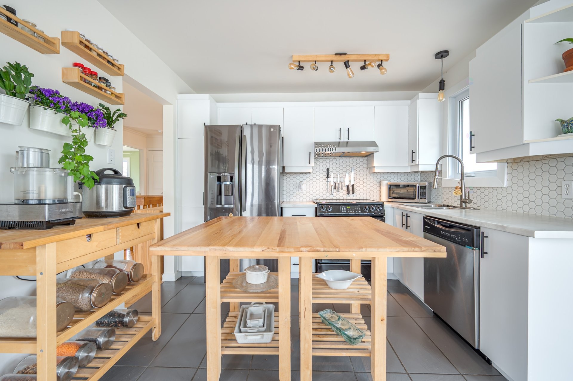 Kitchen with butcher-block island, white cabinetry, hex tile backsplash, stainless appliances